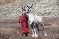 Little tsaatan boy playing with his family`s reindeer.