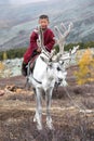 Little tsaatan boy riding with his family`s reindeer.