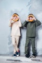 Little twin boys playing and dreaming of becoming a spaceman. Portrait of funny kids with bagels on gray wall Royalty Free Stock Photo