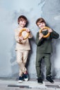 Little twin boys playing and dreaming of becoming a spaceman. Portrait of funny kids with bagels on gray wall Royalty Free Stock Photo