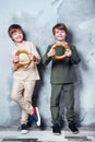 Little twin boys playing and dreaming of becoming a spaceman. Portrait of funny kids with bagels on gray wall Royalty Free Stock Photo