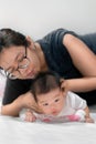 Little two month asian baby lying on stomach and try raised her neck, Asian mother come to help her daughter, Family concept