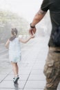 Little Ukrainian girl meets her father from war holding and leading him by hand Royalty Free Stock Photo