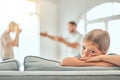 Little unhappy young caucasian girl sitting on sofa while parents arguing in the lounge at home Royalty Free Stock Photo