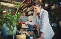 A little water does them a world of good. an attractive young florist watering plants inside a plant nursery with her