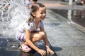 Happy little girl among the splashes of water of the city fountain Royalty Free Stock Photo