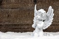 Little white angel on wooden background in snow Royalty Free Stock Photo