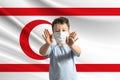 Little white boy in a protective mask on the background of the flag of Turkish Republic of Northern Cyprus. Makes a stop sign with Royalty Free Stock Photo