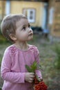 A little white girl holding a brush of Rowan berries. Country house