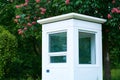 Little white guard booth in green spring park with pink sweet chestnuts. The room for work.