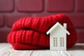 Little white house with red crochet scarf. Heating in winter, thermal insulation of building or dwelling.