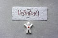 Little white man with heart and valentine card on gray paper background