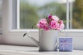 Little white watering can with roses and blue gift box near the