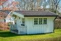 little white wooden summer house in the garden with green grass and trees at the background Royalty Free Stock Photo