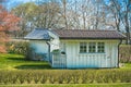 little white wooden summer house in the garden with green grass and trees at the background Royalty Free Stock Photo