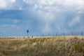 Little Windmill in a golden wheat fied against a blue sky with clouds