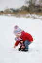 Little winter baby girl touching the snowball Royalty Free Stock Photo