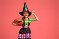 Little witch with a pumpkin on pink background
