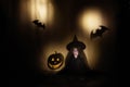 Little witch sits and is afraid of shadows in the form of pumpkin and bat. Halloween holidays concept Royalty Free Stock Photo