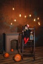 A little witch sits on the stairs with a lantern, smiling Royalty Free Stock Photo