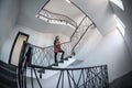 Little woman stays in a huge hall with stairs emergency and evacuation exit. Wide angle Royalty Free Stock Photo