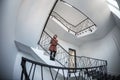 Little woman stays in a huge hall with stairs emergency and evacuation exit. Wide angle Royalty Free Stock Photo