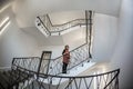 Little woman stays in a huge hall with stairs emergency and evacuation exit. Wide angle Royalty Free Stock Photo