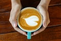 Woman hands holding coffee cup with heart shape latte art on wooden table Royalty Free Stock Photo