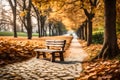 The little wooden bench is empty and situated on a white pathway that is covered in leaves Royalty Free Stock Photo