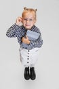 Cropped portrait of cute little girl in casual clothing and stylish glasses isolated over gray background Royalty Free Stock Photo