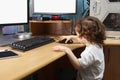 Little 2 3 year old baby girl in white clothers draws at the home computer in graphics drawing tablet. two monitors. The child is Royalty Free Stock Photo