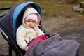 A little year-old girl looks on frowningly from a stroller