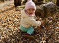 A little year-old girl plays outside with a carved wooden statue