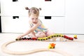 Little 2 years girl playing toy wooden railroad at home