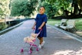 Little 5 years old African kid girl walk and playing with her toy stroller in park. Cute little dark skinned baby girl Royalty Free Stock Photo