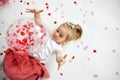Little 2 years old girl playing with balloon with heart shape papers inside it and around Royalty Free Stock Photo