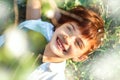 Little 7 years old smiling girl with stylish short haircut laying down in grass under blooming cherry tree in spring. Happiness Royalty Free Stock Photo