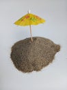 Little yellow umbrella sticking in a pile of beach sand on a white background Royalty Free Stock Photo