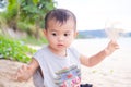 Little young boy child cute about 2 year old sitting on sand beach at coast with blur ocean sea nature background. he play with Royalty Free Stock Photo