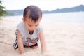 Little young boy child cute about 2 year old sitting on sand beach at coast with blur ocean sea nature background. he play with Royalty Free Stock Photo