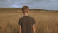 Little young dreamy boy walking in the picteresque field beautiful landscape yellow grass