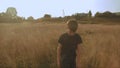 Little young dreamy boy walking in the picteresque field beautiful landscape yellow grass