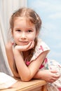 Little young happy smiling school girl smiling, leaning on a table with hand under her chin portrait. Smug smirk expression Royalty Free Stock Photo