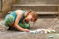 Little young school age child drawing with chalk on the concrete sitting on the ground. Art therapy, sensory integration simple