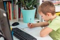 Little young school boy working at home with a laptop and class notes studying in a virtual class. Distance education and learning Royalty Free Stock Photo