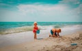 Littlegirl and boy play with sand on beach