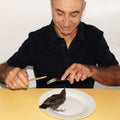 A live bird on a plate looks at a man with a knife and fork