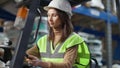 Live camera follows confident female driver autoloader operator sitting in warehouse forklift. Serious professional