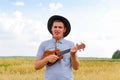 Live concert. Young beautiful caucasian man playing ukulele outside. Handsome hipster guy plays ukulele guitar on nature Royalty Free Stock Photo