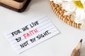 We live by faith, not by sight, handwritten Christian quote on paper with pencil, flowers, and closed holy bible book Royalty Free Stock Photo